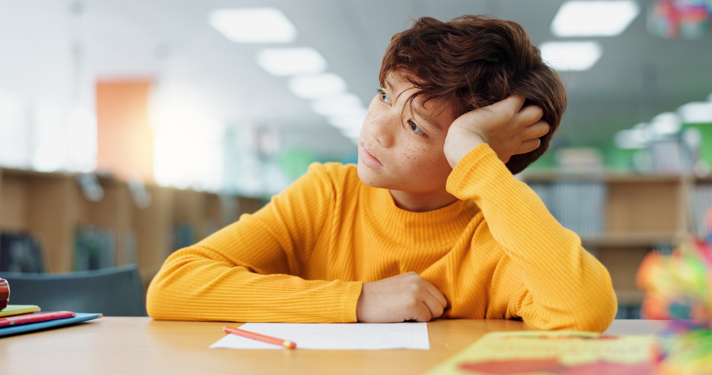 boy with adhd sitting at a table at school.