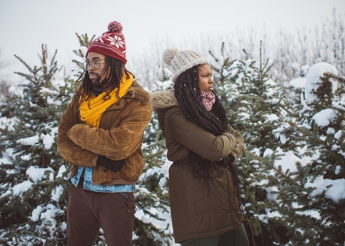 Couple arguing while choosing Christmas tree in Christmas tree farm, it is snowy weather, daytime.