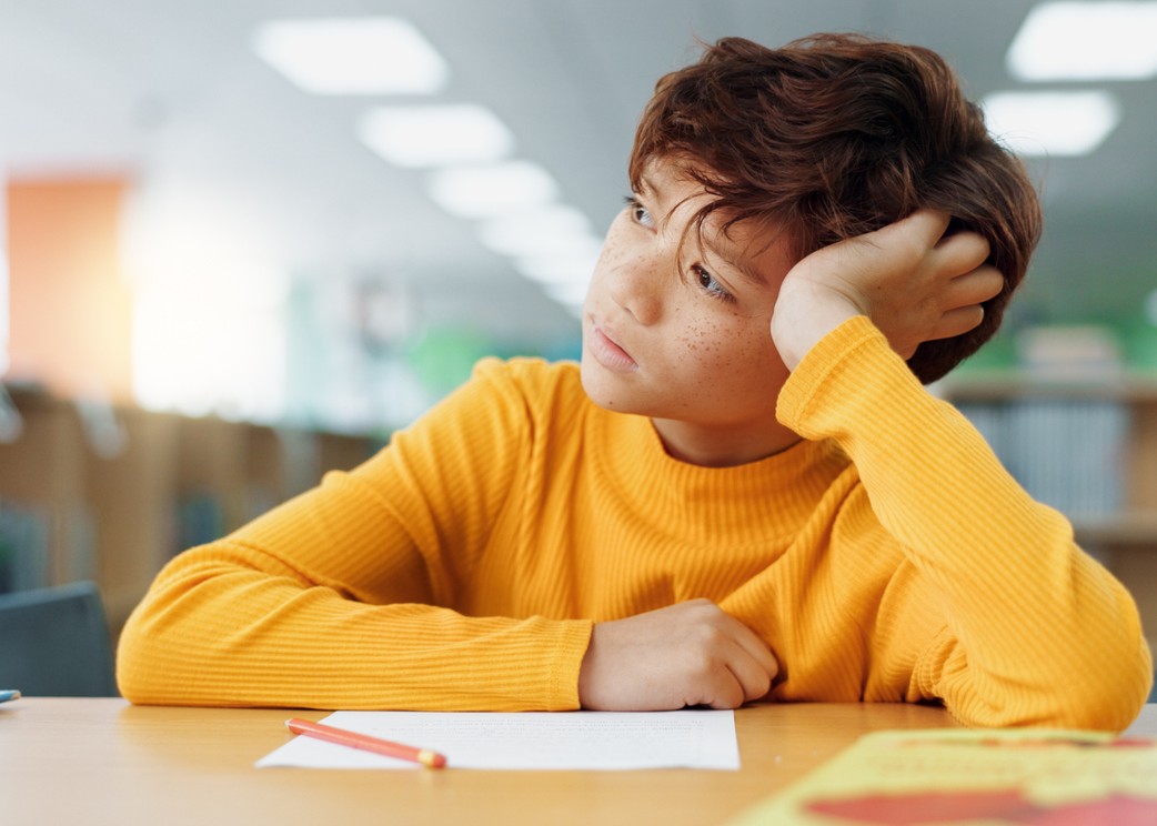 boy with adhd sitting at a table at school.