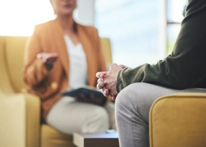 Man, hands and listening for therapy, sofa or advice from woman for mental health, psychology or care. Psychiatrist, patient and frustrated in clinic, session or couch for help, anxiety or depression